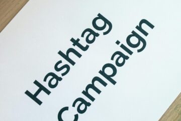 Creative desk setup featuring a hashtag campaign paper and a motivational notebook, ideal for marketing and planning themes.