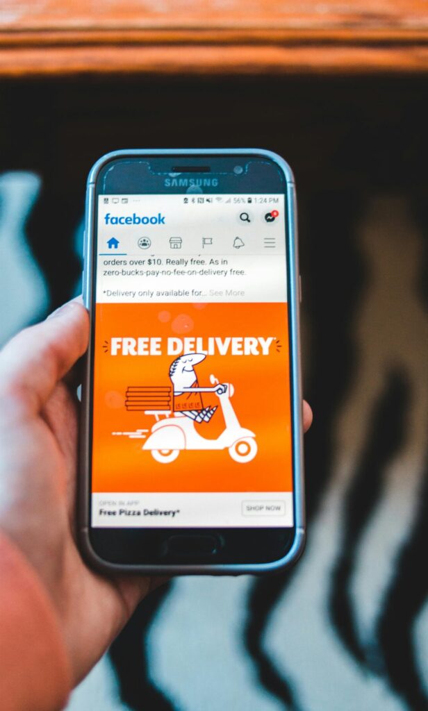 Hand holding a smartphone displaying a Facebook ad for free delivery, capturing modern digital communication.